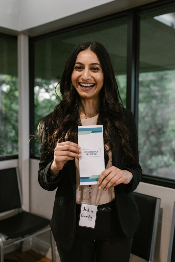 A Woman Holding a Brochure While Standing Near the Glass Windows